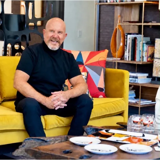 Travis Smith seated on a mustard sofa
